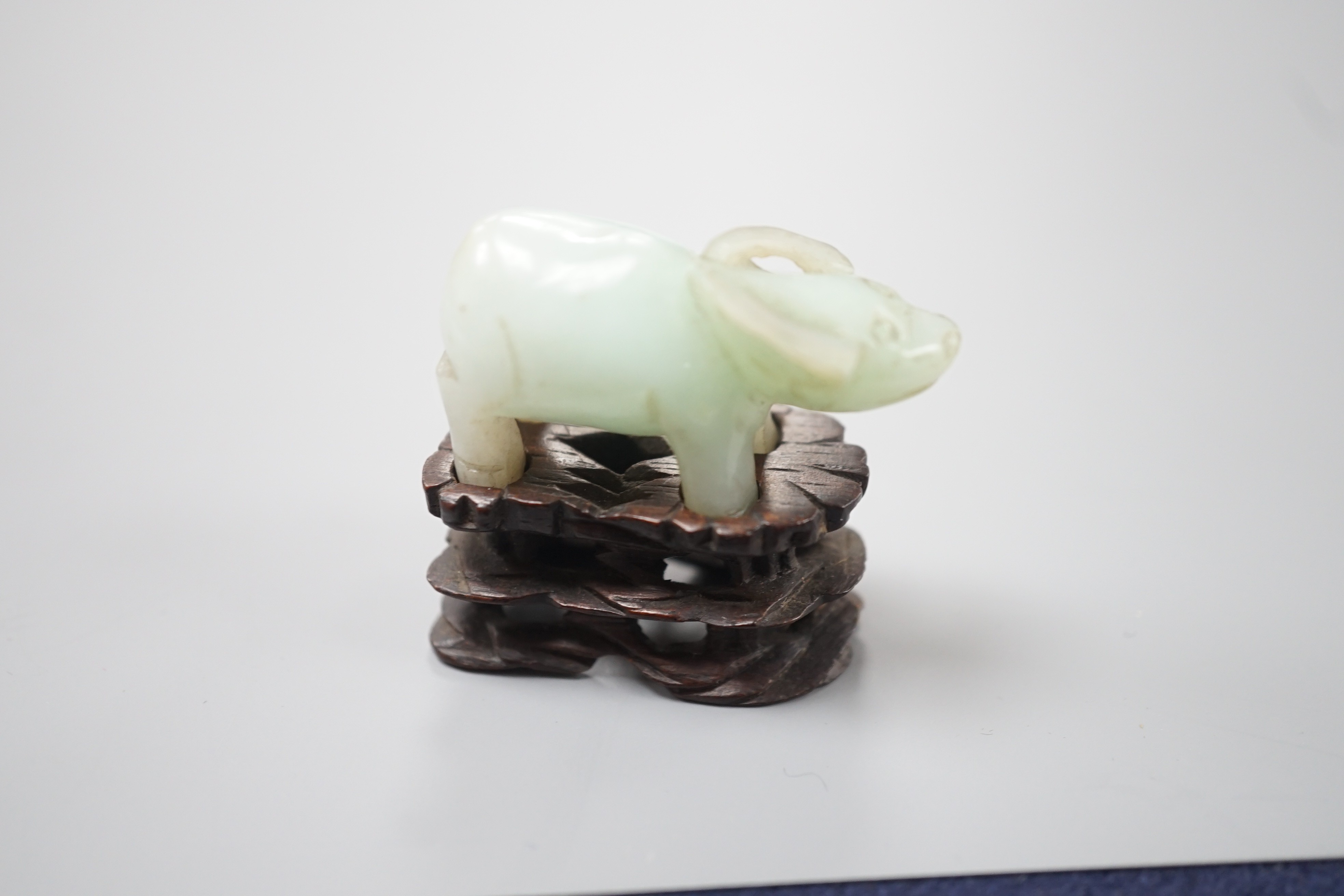 A small Chinese jade figure of a buffalo, late 19th/early 20th century, 3.8cm long, wood stand